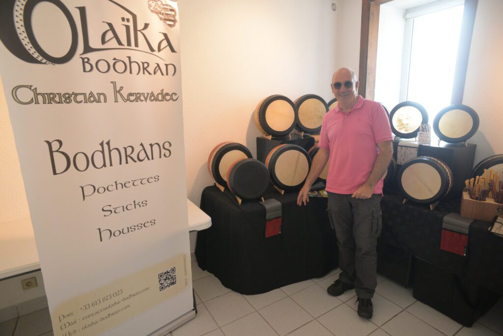 Homme souriant à côté de tambours Bodhrans exposés