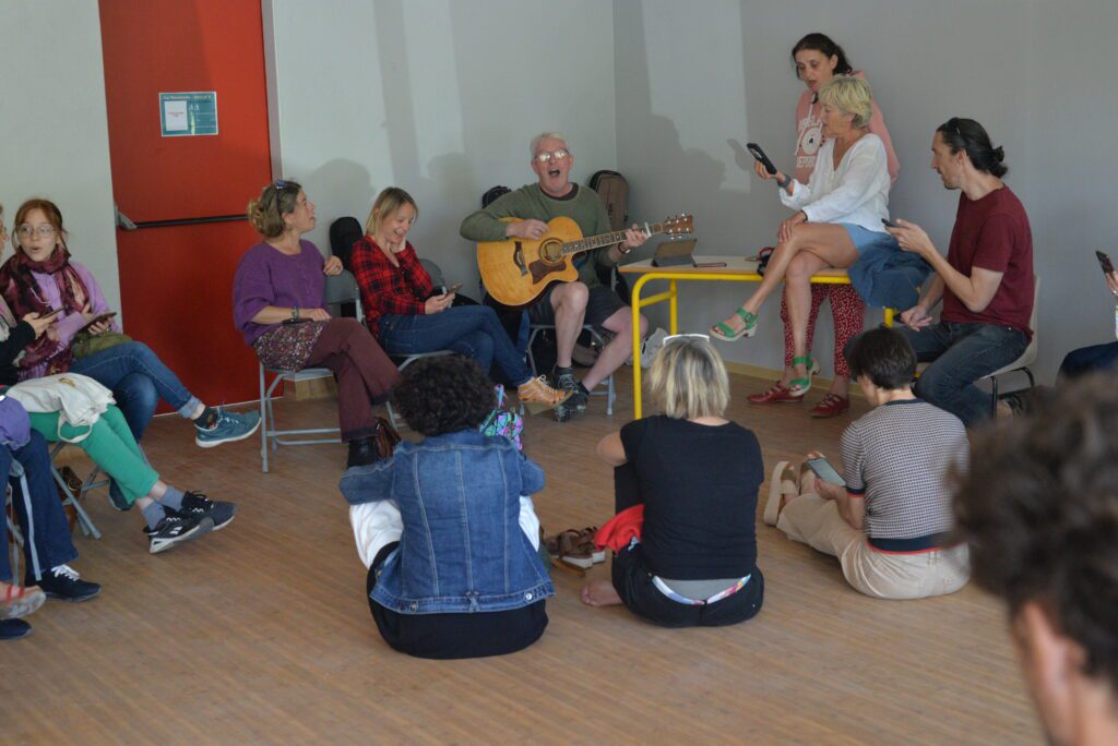 Homme jouant de la guitare pour un groupe assis
