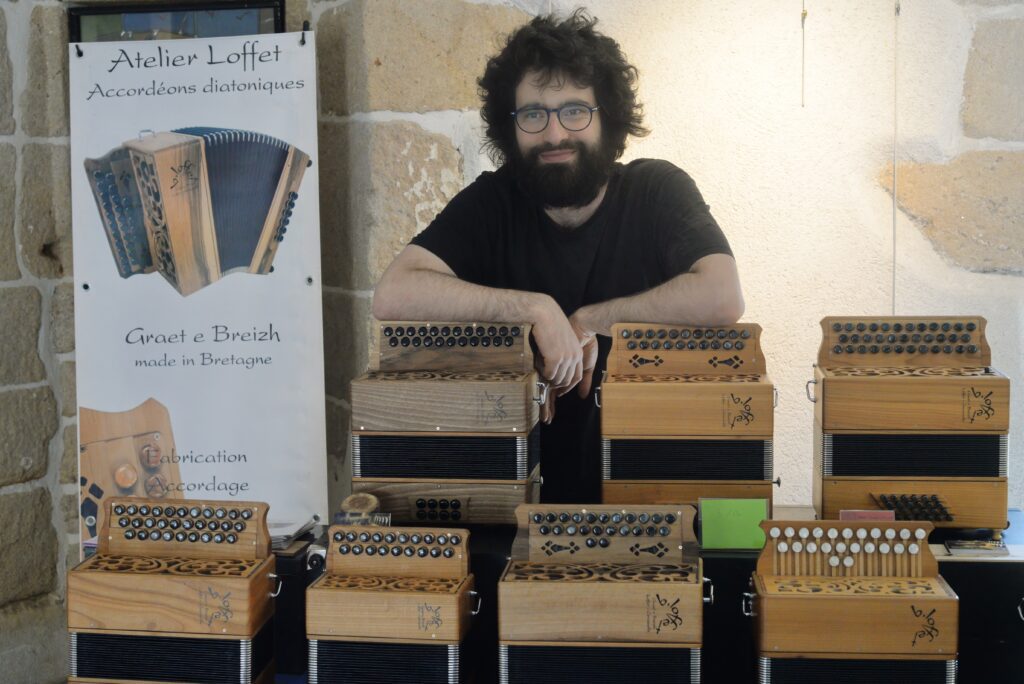 Artisan souriant avec accordéons diatoniques en atelier
