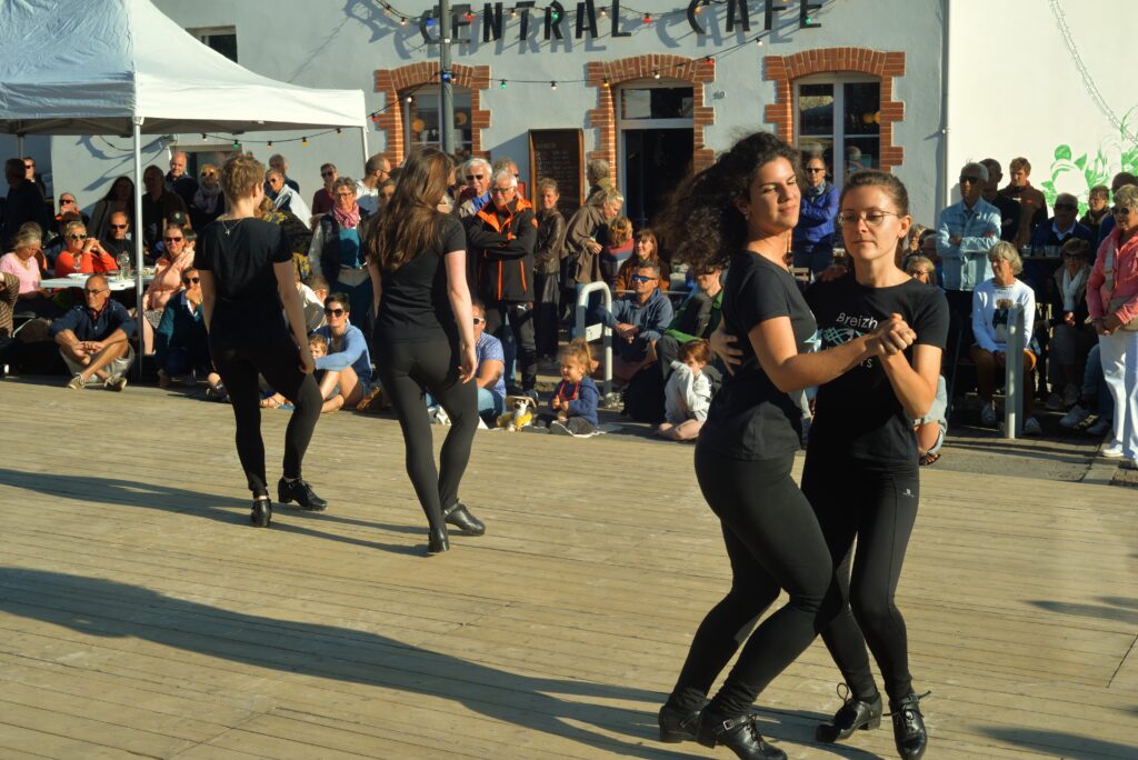 Deux femmes dansent devant un public ensoleillé