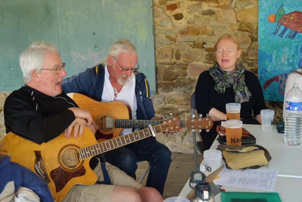 Trois amis jouent de la guitare et chantent ensemble.