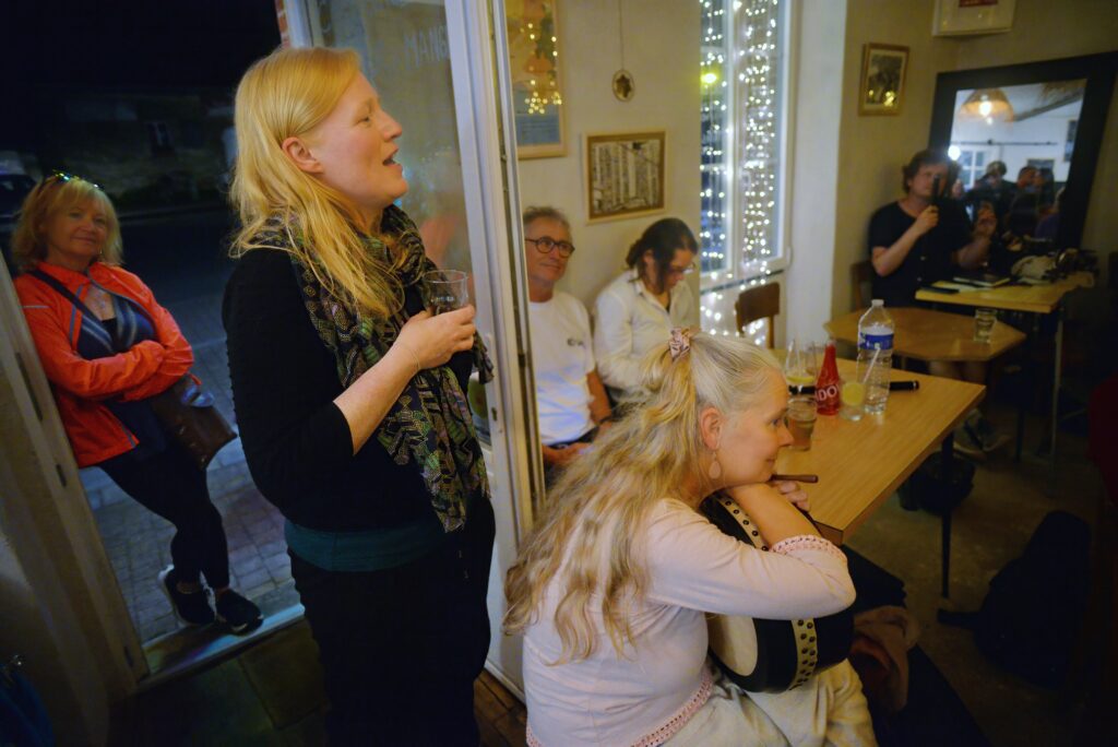 Femme chante dans un café animé avec guirlandes lumineuses